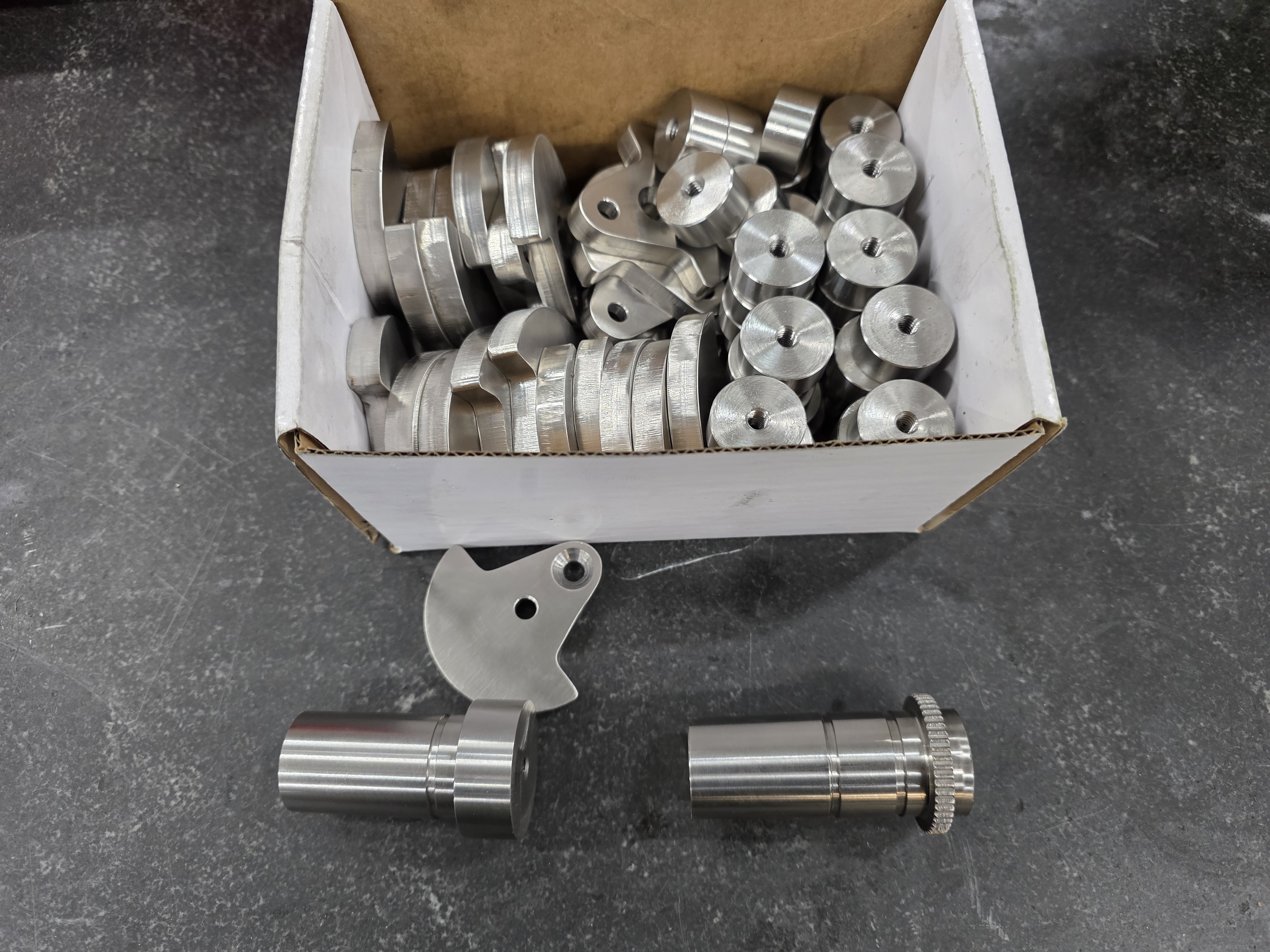 Bulk turned metal spacers and hardware in a production container.