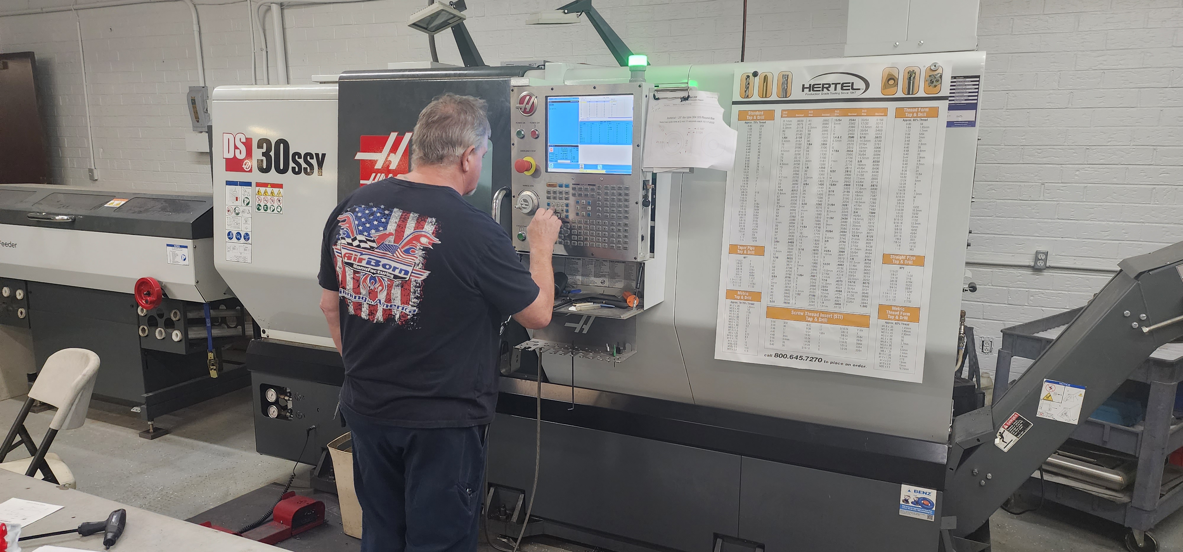 CNC turning lathe production cell with operator and shop setup board.