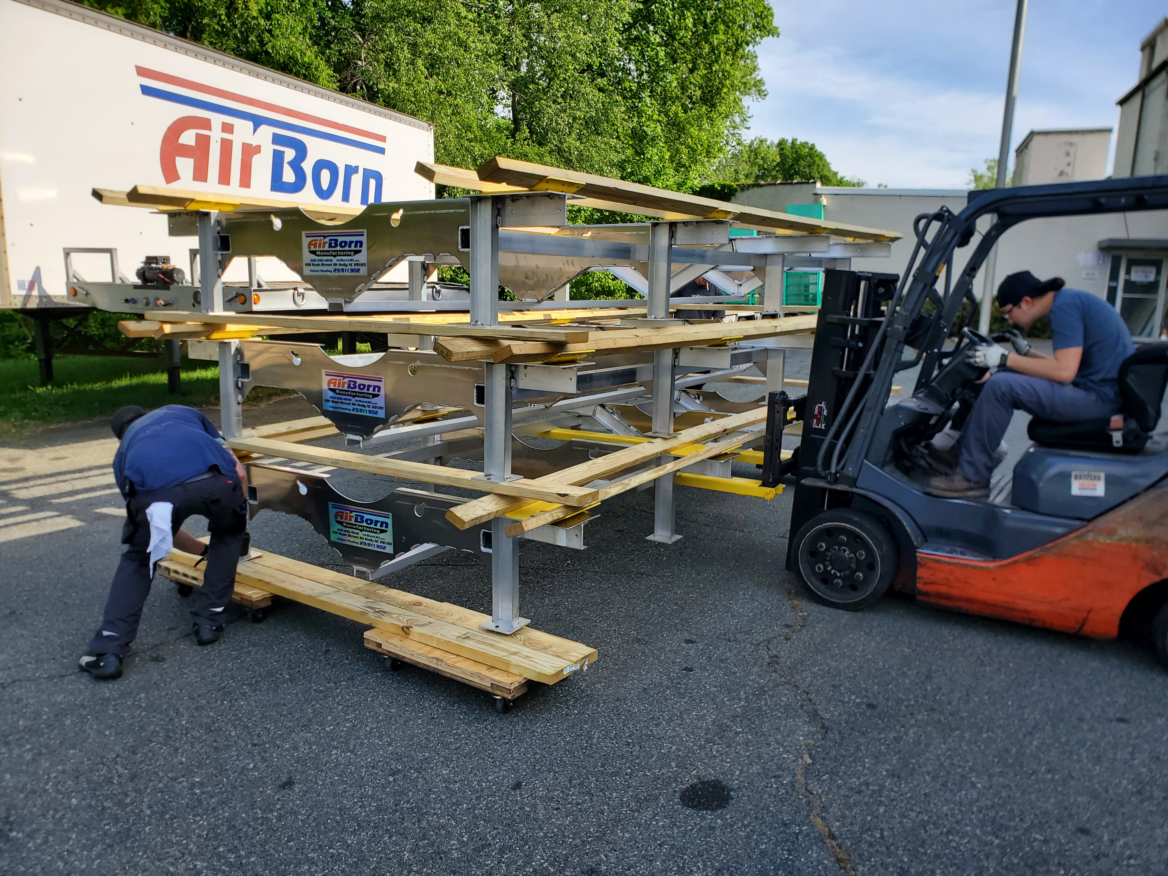 Forklift staging a welded metal frame assembly outside a shop facility.
