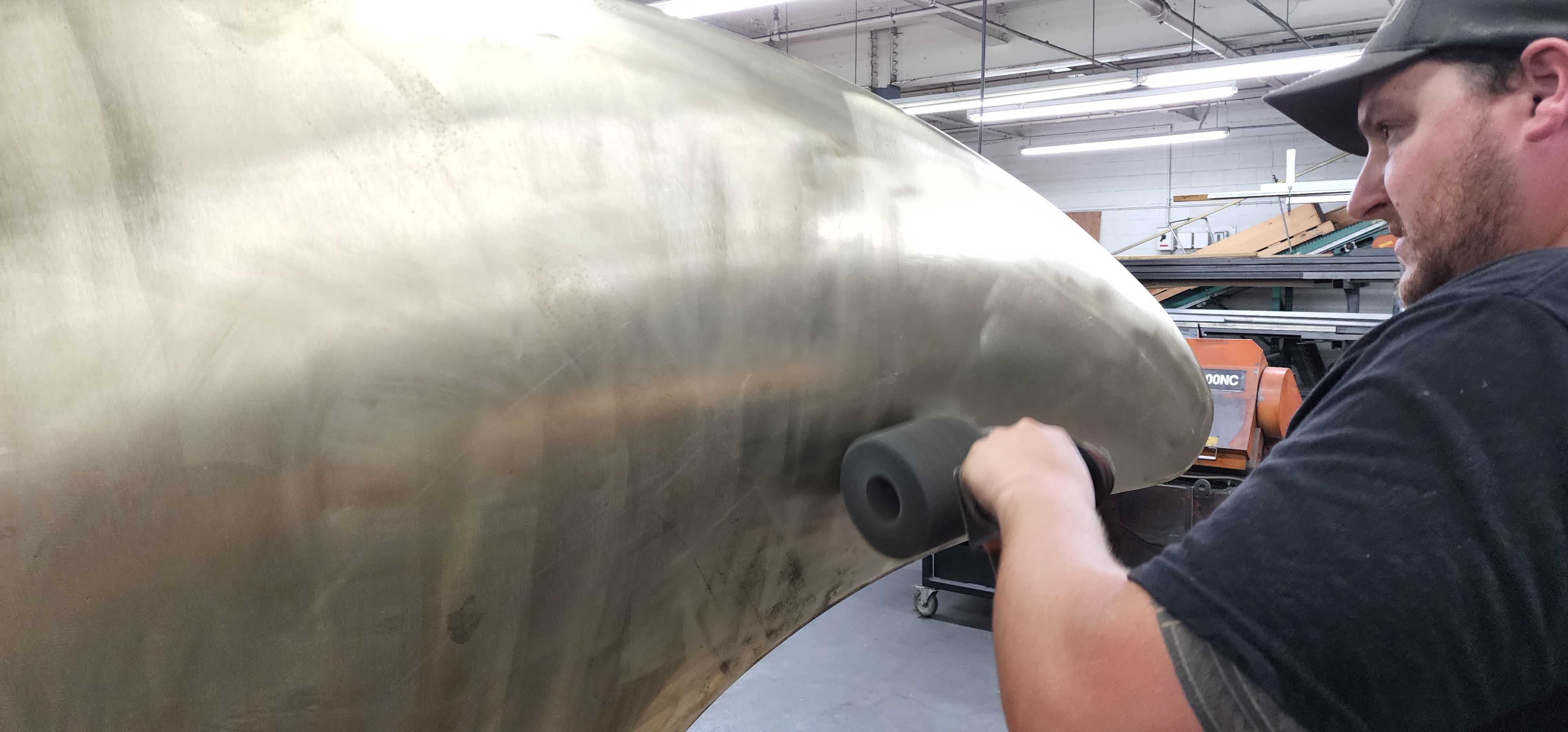 Technician checking the surface of a large formed metal component.