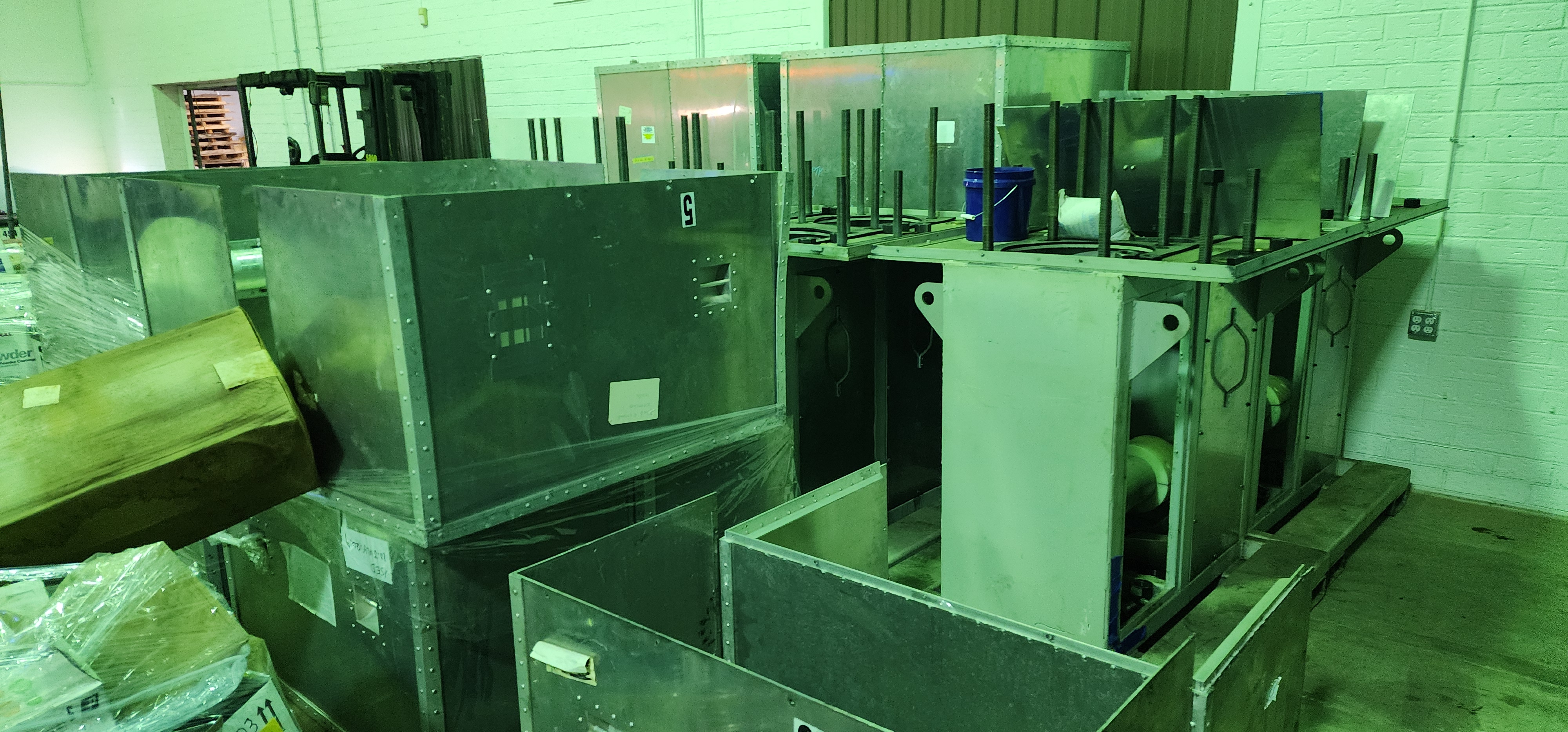Green painted sheet metal enclosures staged together in the shop.