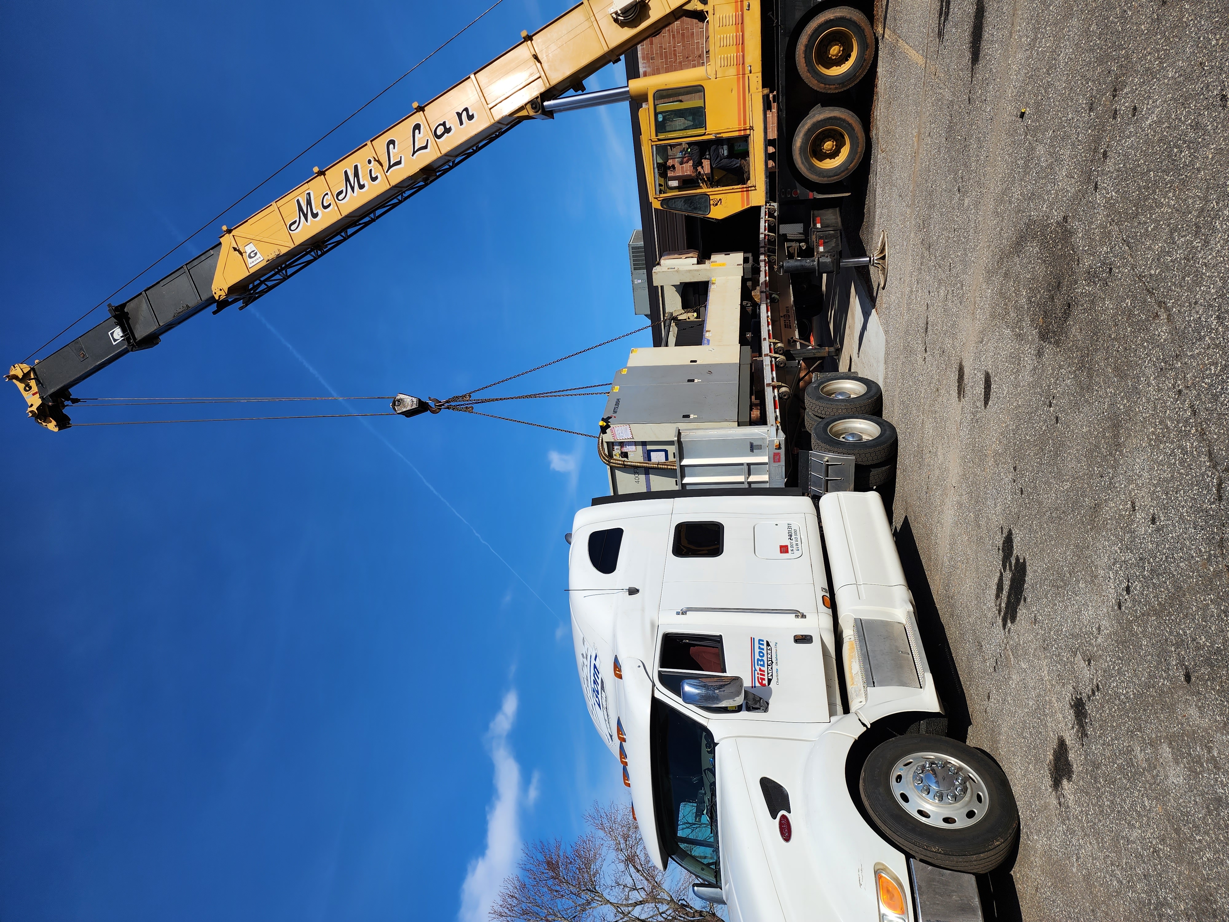 Industrial crane loading fabricated metal equipment for transport.