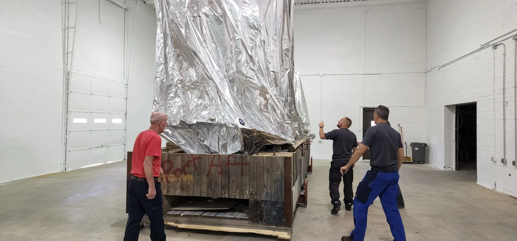Large fabricated component wrapped and staged on a crate for shipping preparation.