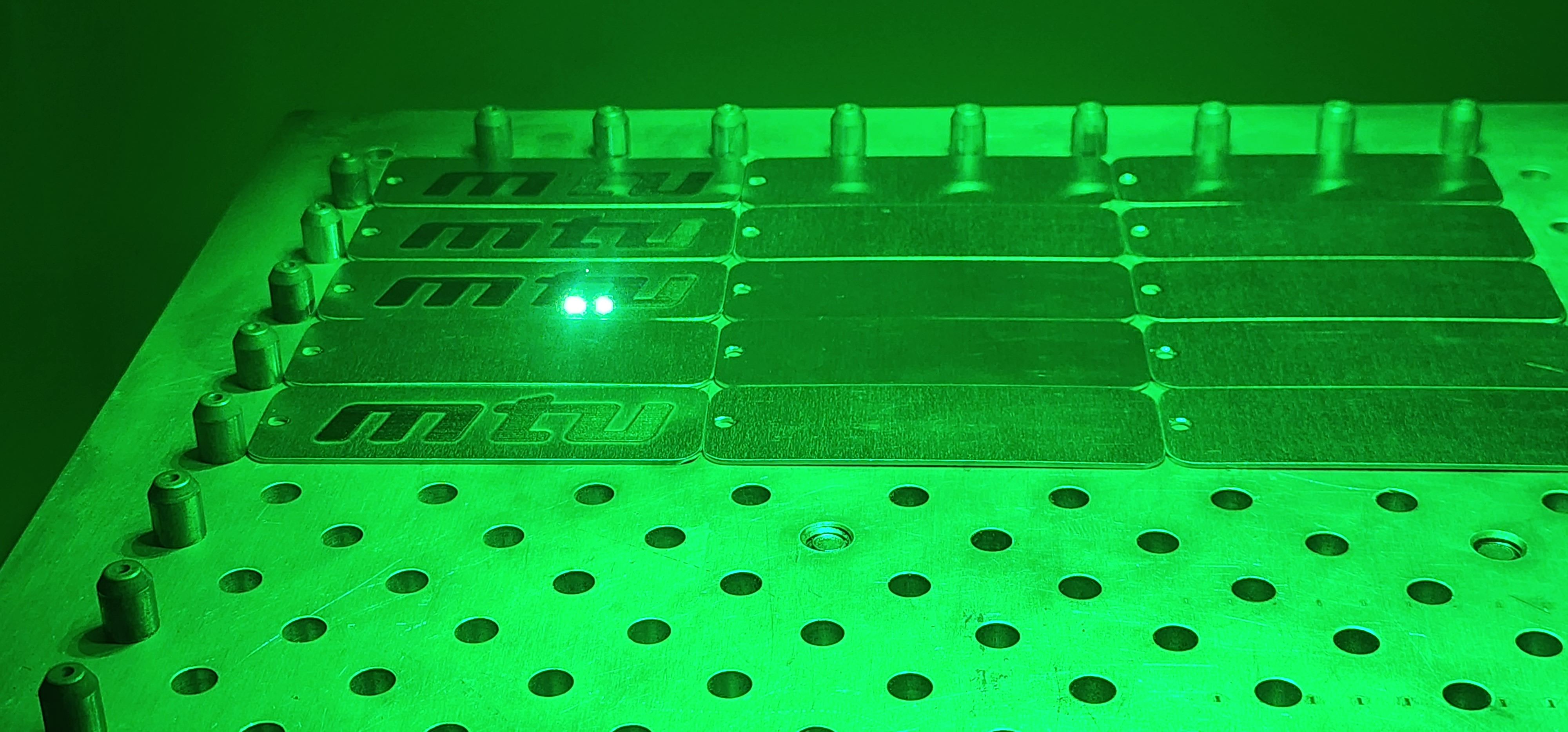 Laser-cut sheet metal nesting table with green cutting light visible.