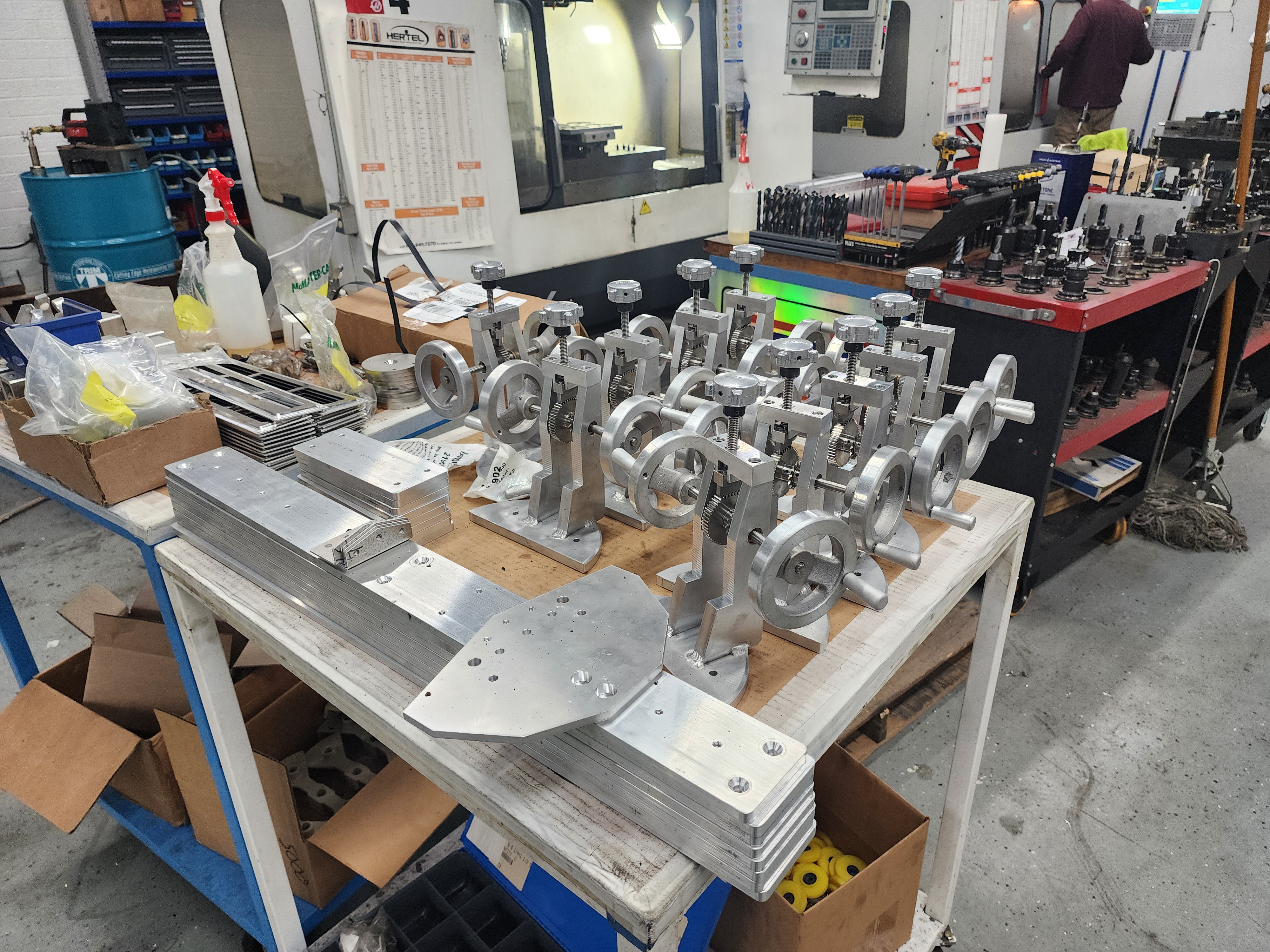Machined metal brackets and hardware assemblies arranged on a production table.