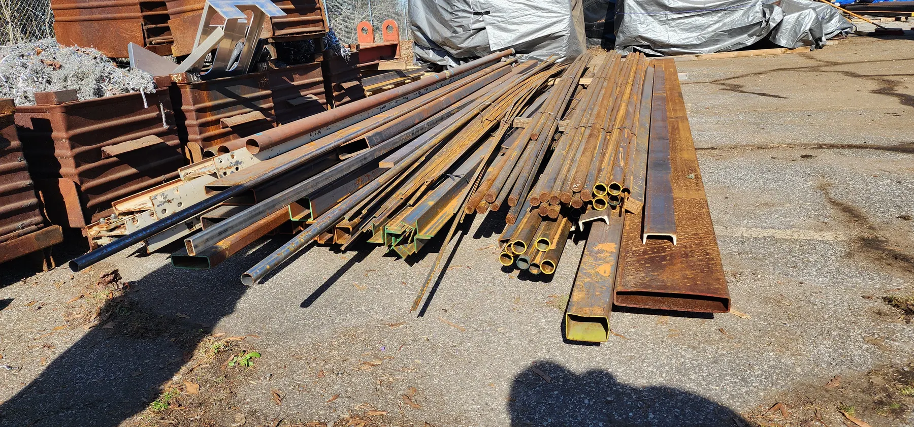 Raw steel bar stock staged outdoors for metal fabrication work.
