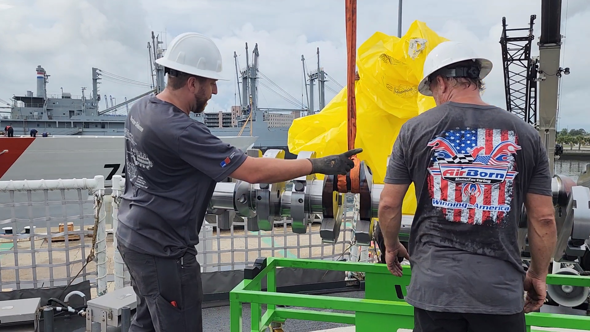 Shipboard metal assembly installation support with team members handling equipment.