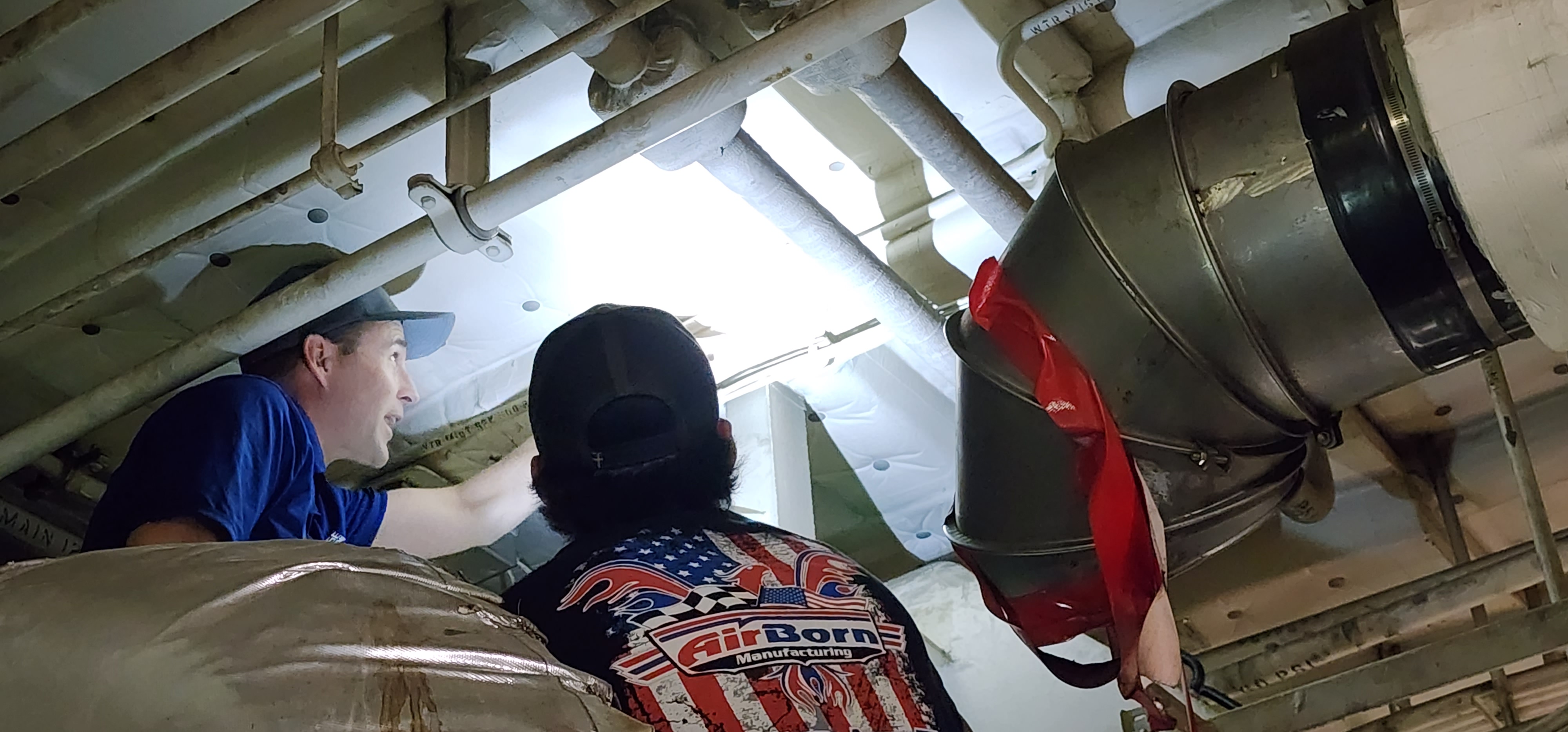 Metal fabrication installation work taking place inside a shipboard mechanical space.