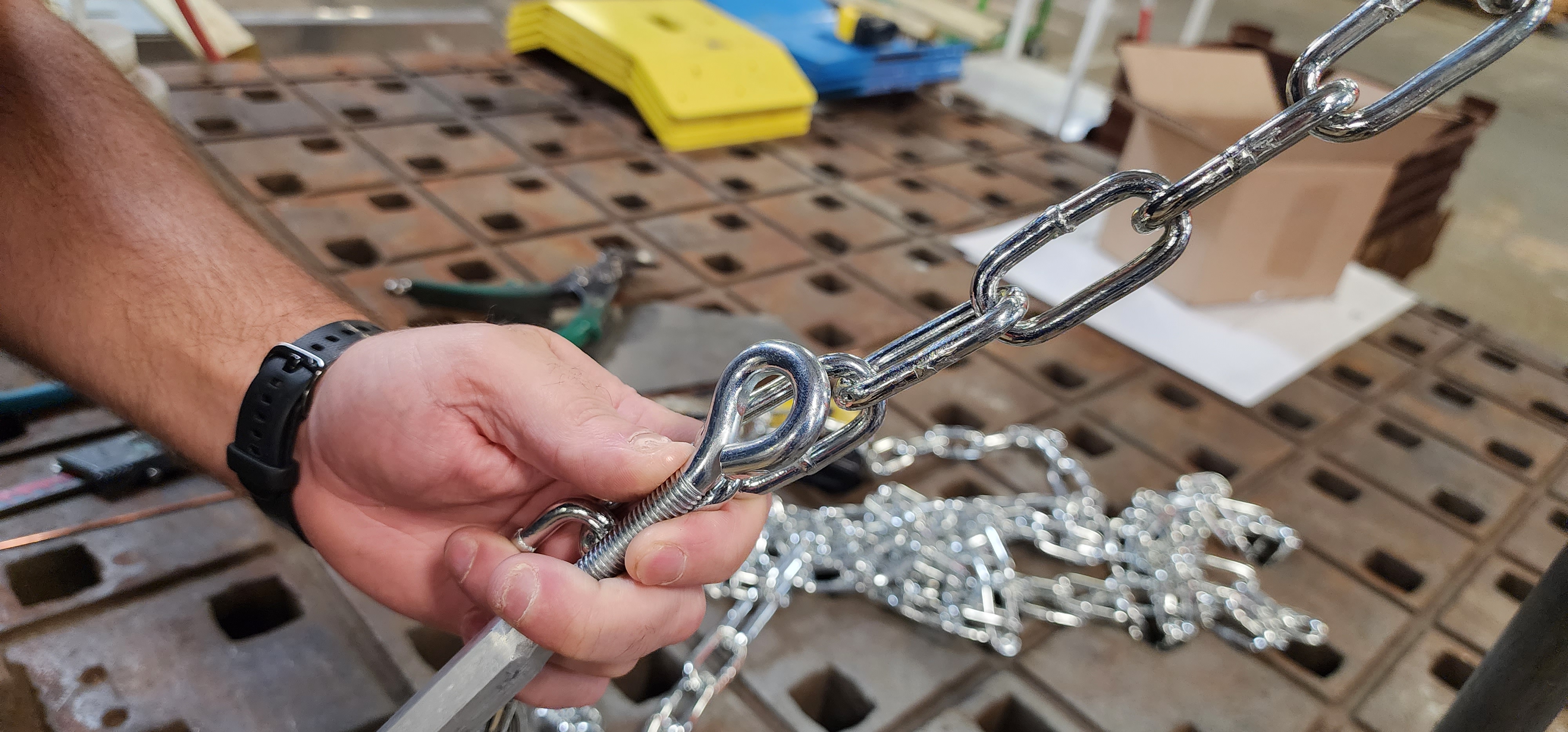 Stainless metal chain and hardware laid out for manufacturing assembly work.