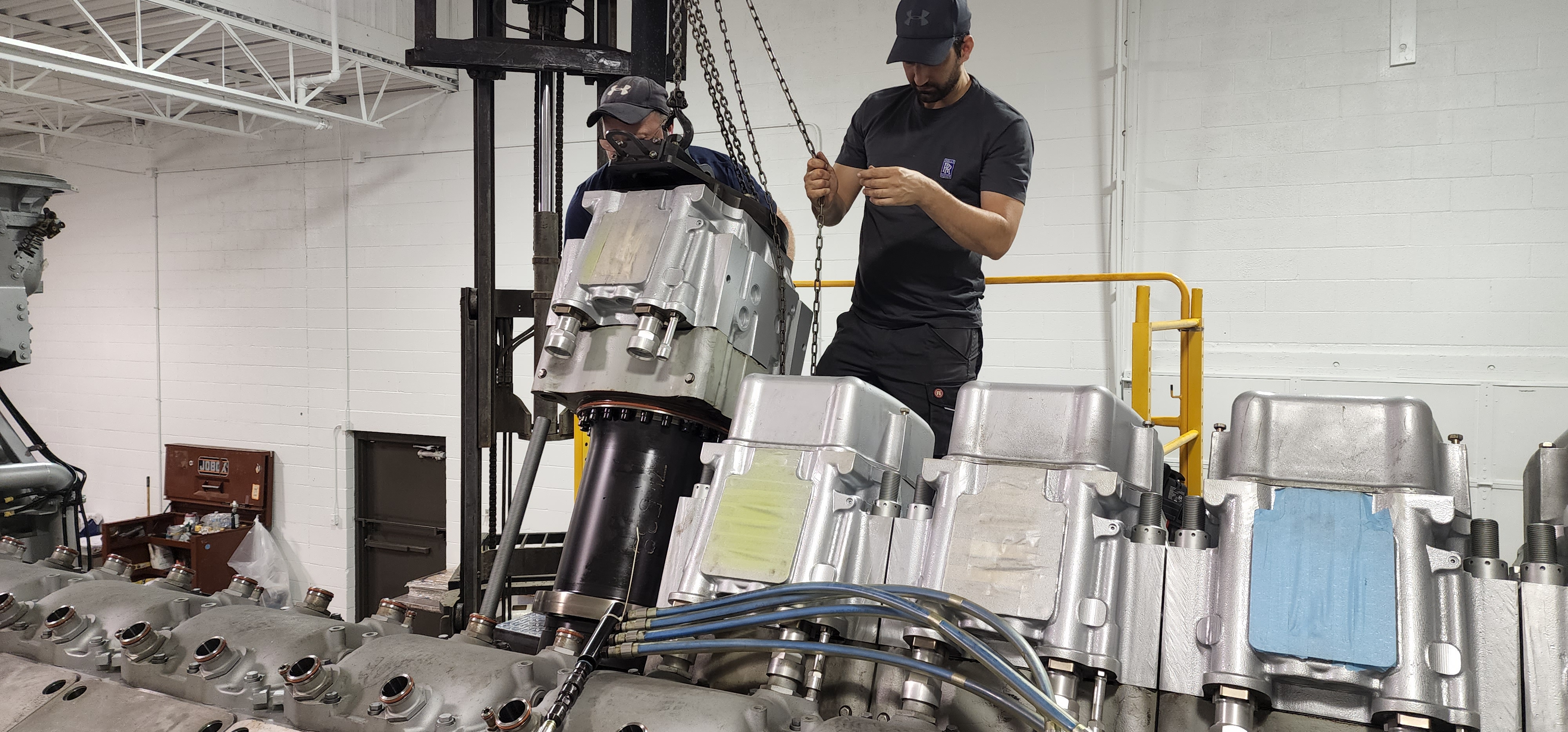 Technician aligning a machined assembly with lifting equipment in place.