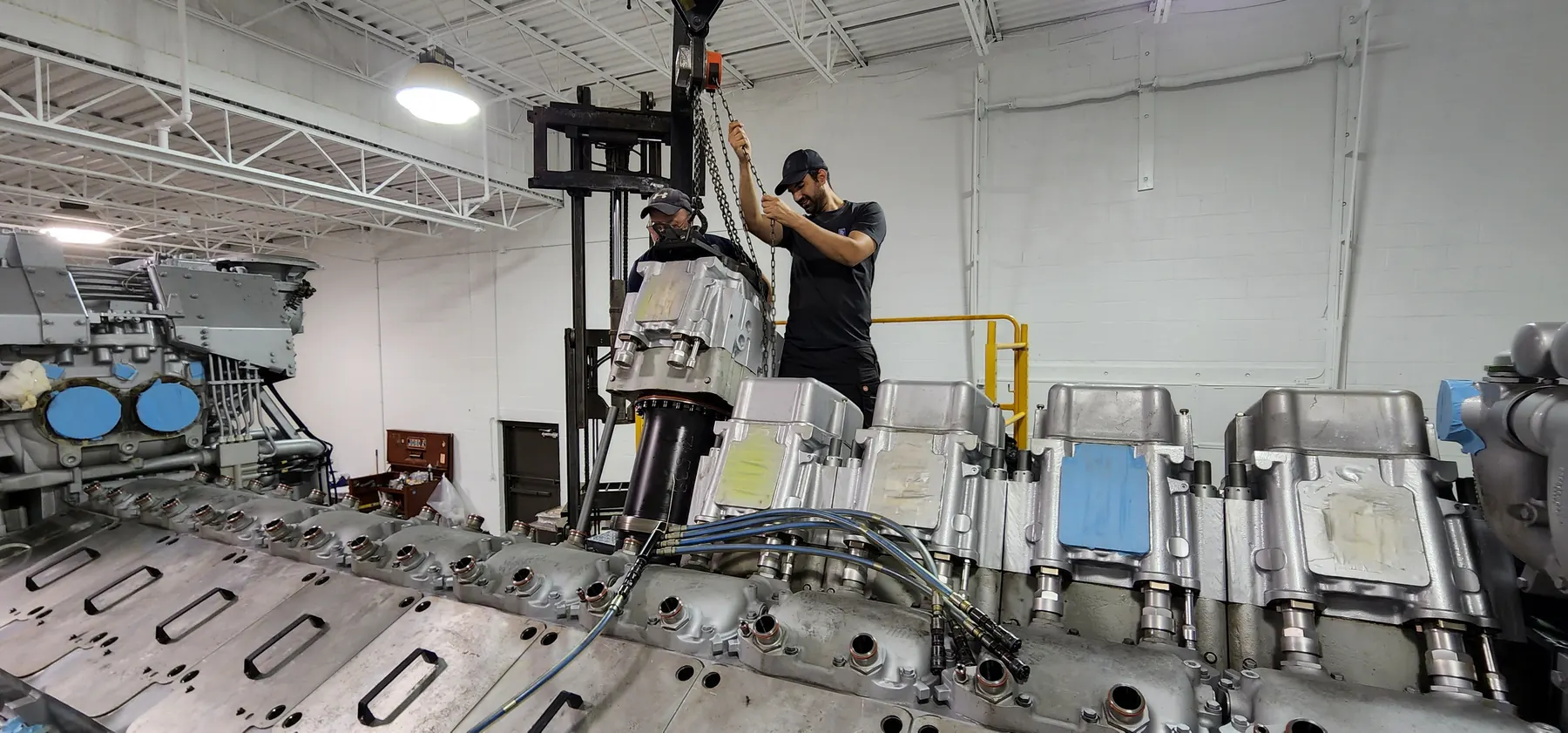 Technician fitting a large machined component during shop assembly work.