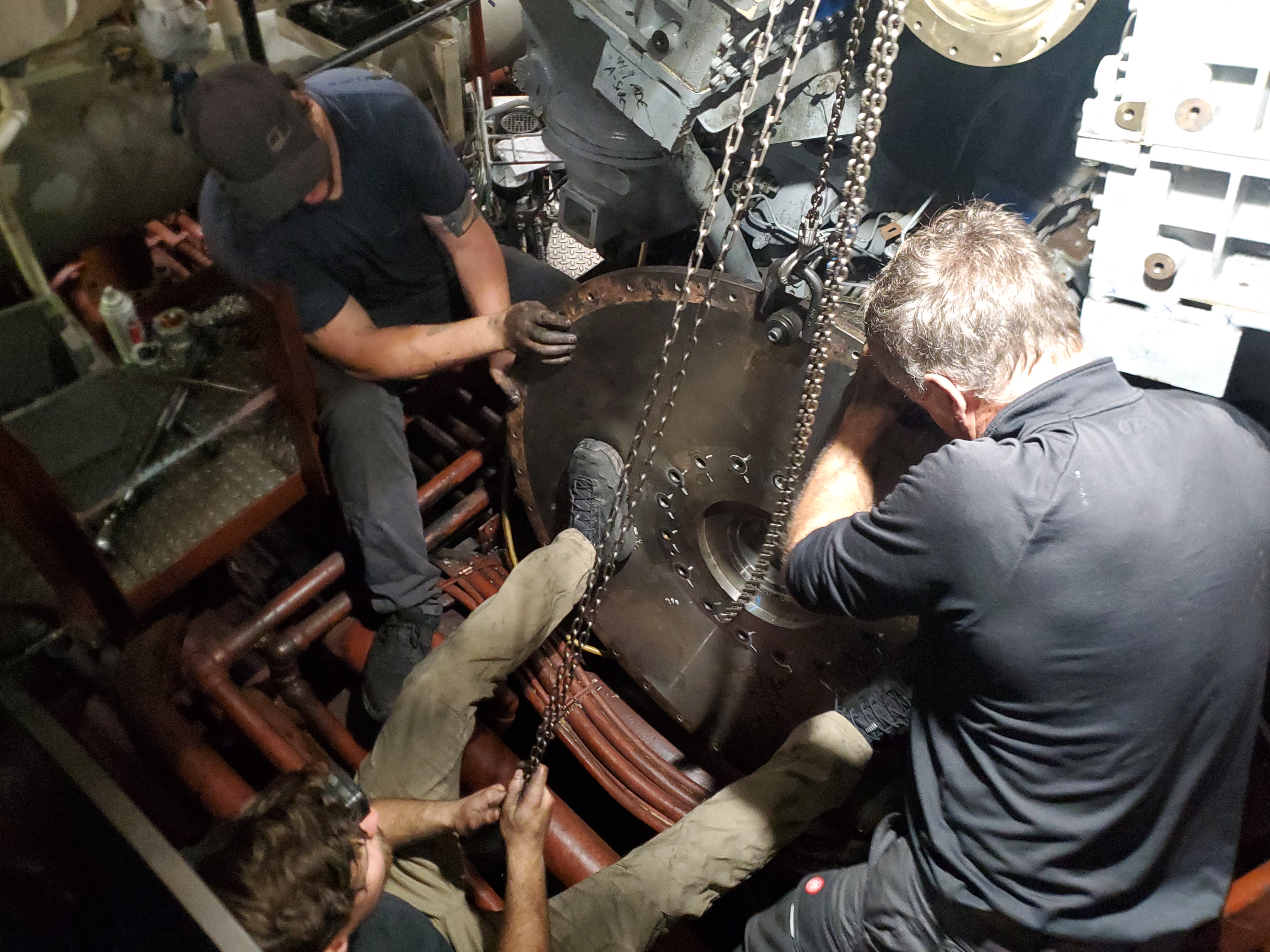 Technician installing a metal piping assembly inside industrial equipment.